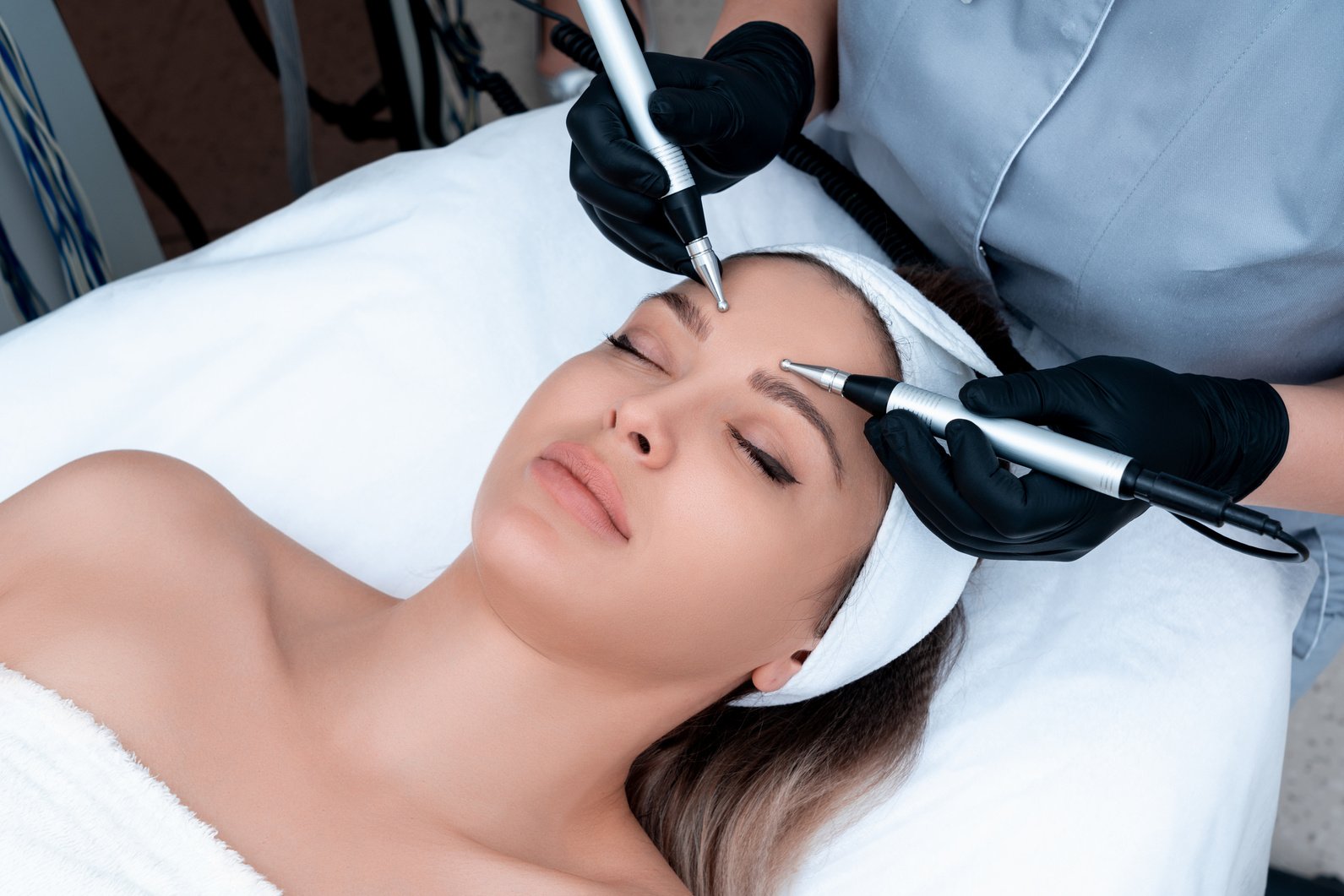 Cosmetology. Beautiful Woman at Spa Clinic Receiving Stimulating Electric Facial Treatment from Therapist. Closeup of Young Female Face during Microcurrent